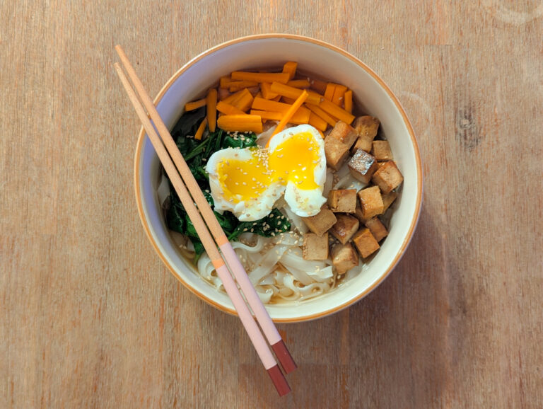 Bol de ramen végétarien maison à la citronnelle avec tofu caramélisé, épinards frais, carottes râpées et œuf mollet.