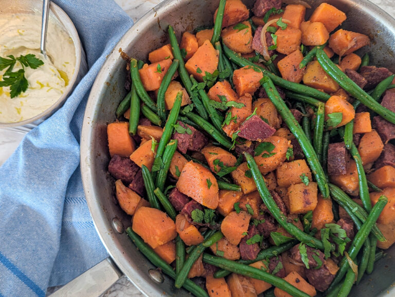 Poêle remplie d’une poêlée de patates douces, chorizo et haricots verts, avec une crème ricotta citronnée servie à côté.