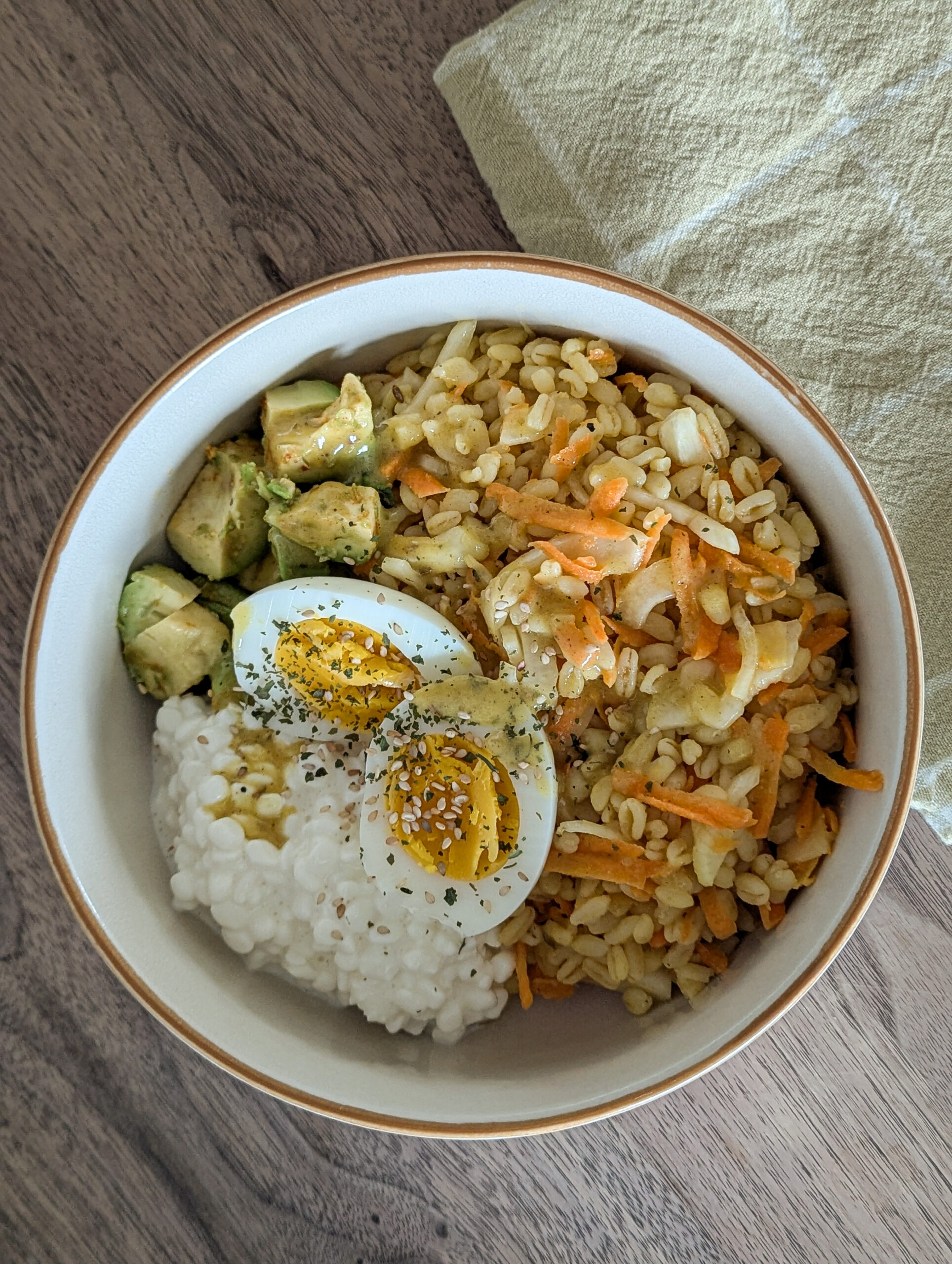 Bowl tiède de blé Ebli avec carottes, fenouil, avocat, cottage cheese et œuf dur, assaisonné d’une vinaigrette à l’orange, vu de dessus.