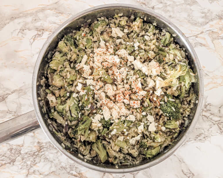 One pot de riz sauvage aux brocolis et feta, servi directement dans une casserole, vu de dessus sur un plan de travail clair.
